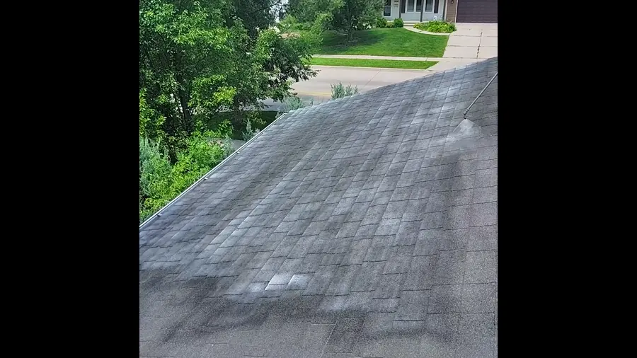 Asphalt shingle roof slope showing patchy wear and granule loss