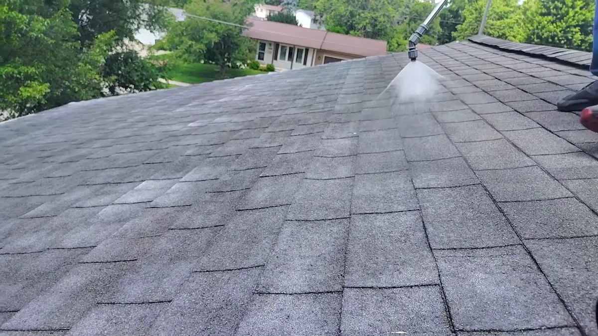 Spray fan of soy-based treatment hitting dry asphalt shingles